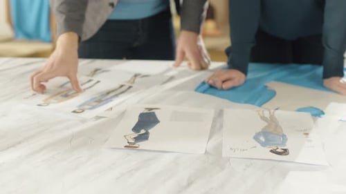 Hands Close-up of a Female and Male fashion, designer, Choosing Sketches for Their New Clothing Co