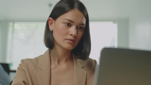Woman Typing and Taking Notes at Desk