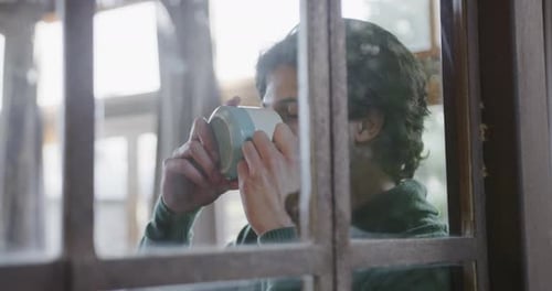 Man Drinking Coffee by a Paneled Window
