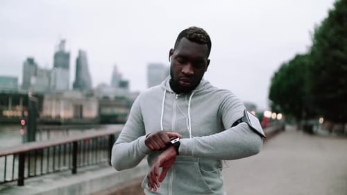 Sporty Black Man Runner With Smart Watch Walking On The Bridge In A City.