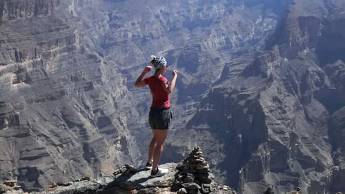 Frau steht mit offenen Armen auf einem Canyon-Felsen und genießt Freiheit und schöne Aussicht