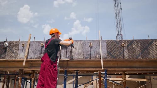 Vue arrière d'un ouvrier du bâtiment professionnel portant un casque de sécurité et une salopette qui fabrique un coffrage avec
