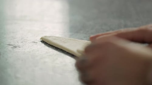 Un boulanger prépare un croissant à partir de pâte feuilletée dans une fabrique de pain. Gros plan des mains masculines avec des tatouages
.