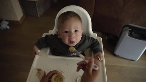 Adorable Infant Eating Food in Highchair