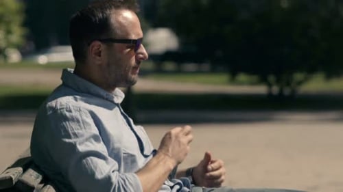 Impatient man checks watch and phone awaiting a late arrival at city cafe
