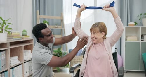 Woman Using Resistance Band in Wheelchair with Assistant