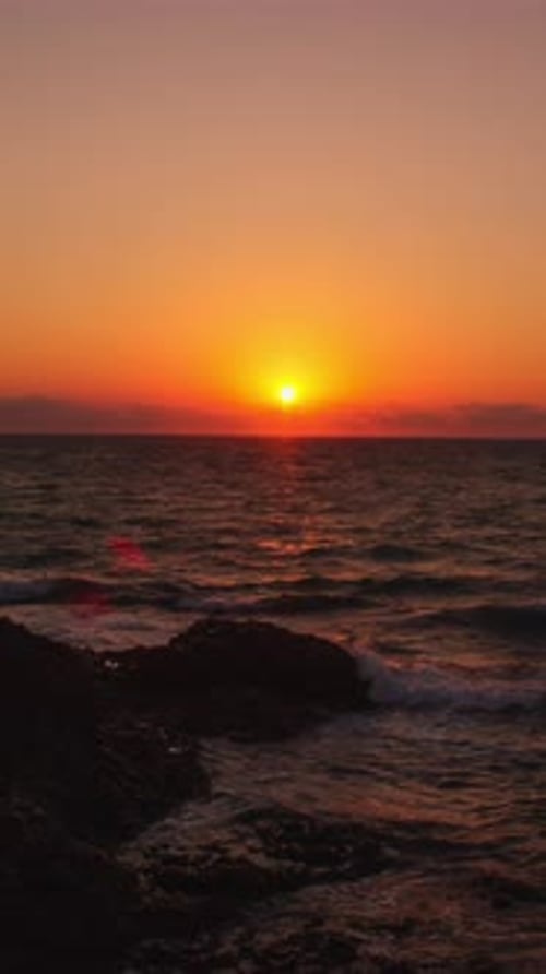 Golden Sunset over Ocean Waves and Rocky Shore