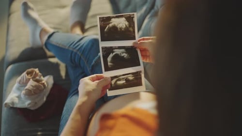 Pregnant Woman Looking at Ultrasound Pictures at Home