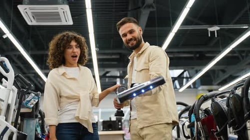 Couple Choosing Cordless Vacuum Cleaner in Electronics Store on Black Friday