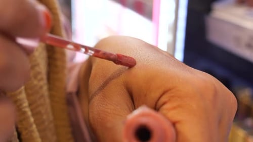 Eine Geste, bei der karminroter Lippenstift auf das Handfleisch einer anderen Person aufgetragen wird