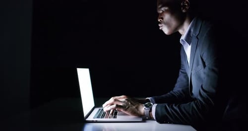 Young Adult Typing on Laptop at Night
