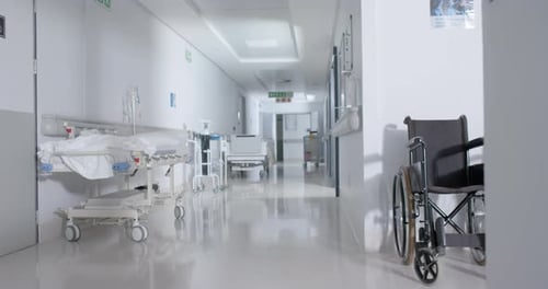 General view of empty hospital corridor with wheelchair and patient beds in slow motion