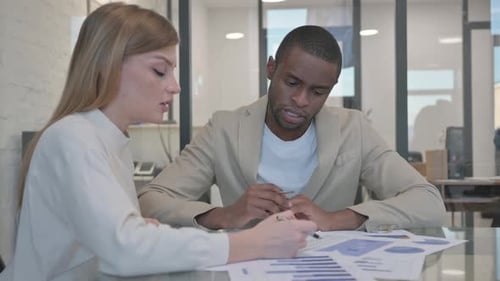 Business Professionals Collaborate on Charts in Office