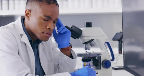 Young Scientist Analyzing Sample with Microscope in Lab