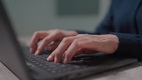 Close up of unrecognizable businesswoman sitting at workplace, drinking coffee and working on laptop