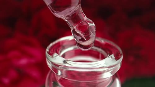 Gotas rosadas que gotean de una pipeta en un recipiente de vidrio Productos abstractos para el cuidado de la piel