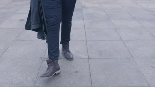 Person Walking on City Sidewalk with Jacket