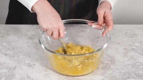 Mixing Ingredients in a Glass Mixing Bowl to Prepare Coconut Banana Pancakes