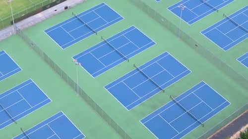 Bright coloured tennis courts seen from drone view above at sunset