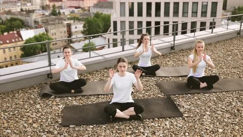 Group Doing Yoga on Rooftop in Urban Setting