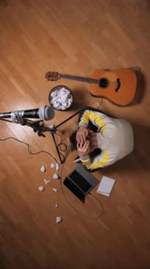 Musician Sits on Floor with Guitar and Microphone