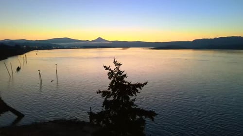 Drone staying in place above a beautiful lake during sunrise, making a 180 degree turn, showing a be