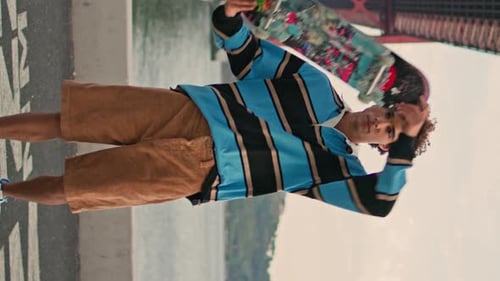 Young Man Posing Skateboard at Water View Quay Skater Looking Camera Vertical
