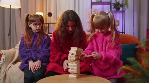 Three Siblings Children Girls Playing with Blocks Board Game Build Tower From Wooden Bricks at Home