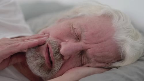 Close up of Old Man with Toothache Lying on Side in Bed