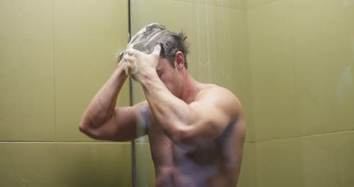 Young Man Washes Out Shampoo From Black Hair in Hotel Shower