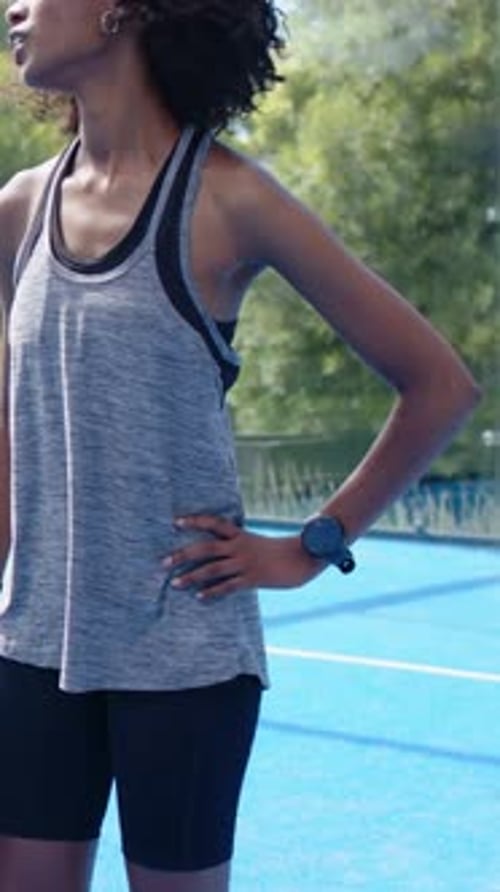 Vertical video: Hearing off-camera shout, skater in tank gesturing on blue court with skateboard