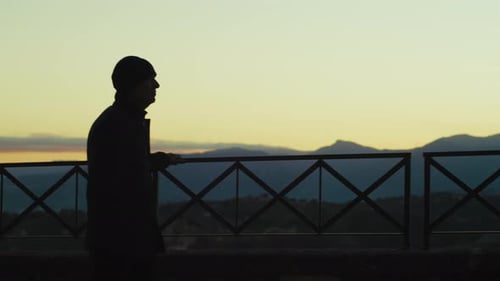 Silhouette Of An Elderly Gentleman Explores A Mountain Balcony At Sunset