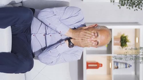 Vertical video of The old man watching TV is afraid.