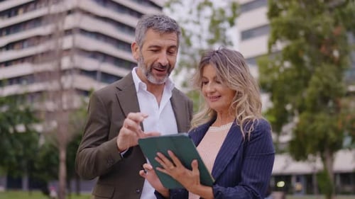 Professionals Discussing Information on a Tablet Outdoors