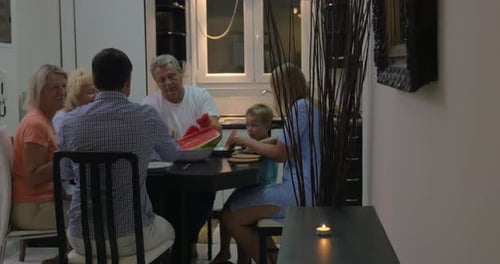 Family Sharing Watermelon Around the Dining Room Table