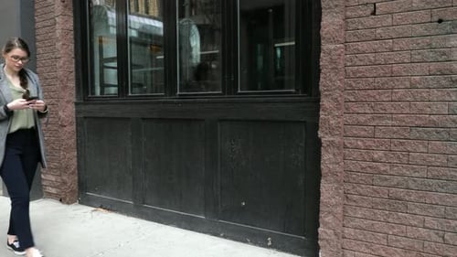 Young Woman with Smart Phone and Backpack Walking on Urban Sidewalk 2024 Years