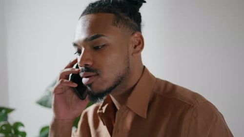 Man with dreadlocks talking on smartphone indoors