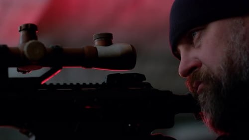 Man with rifle scope in dark red lit room