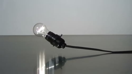 Lightbulb Shatters in Slow Motion on Reflective Surface