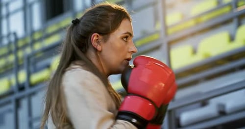The Girl Trains Boxing in the Stadium Using Boxing Gloves