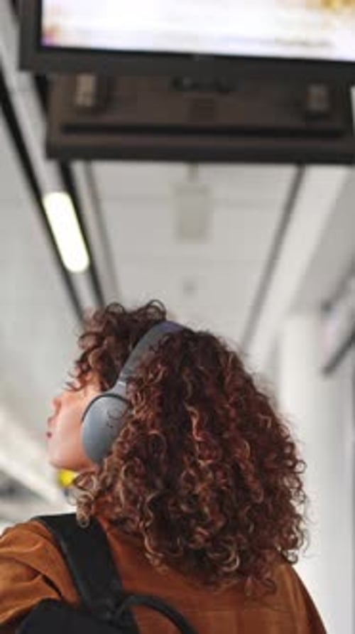 Jeune femme se promenant dans une station de métro lumineuse et spacieuse tout en écoutant de la musique
