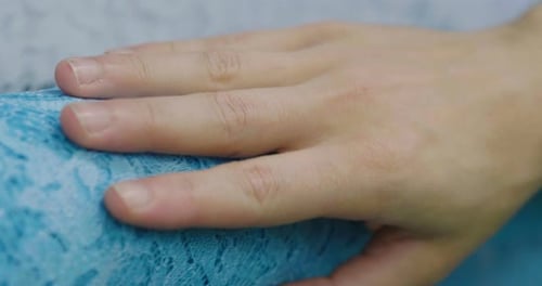 Hand Resting on Light Blue Lace Fabric