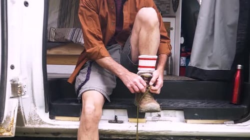Man Lacing Hiking Boot While Sitting in Camper Van