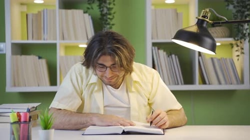 Young Adult Writing at Desk Under Lamp