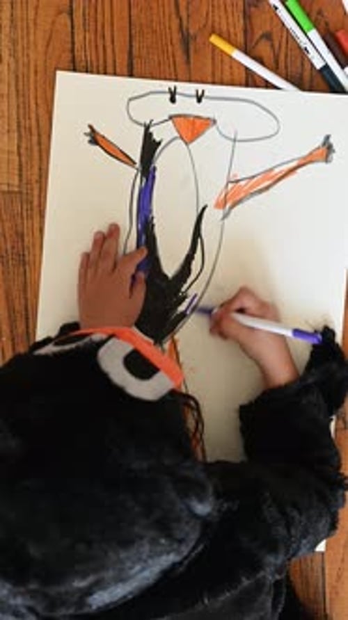 Child Drawing Cartoony Bird with Markers on Floor