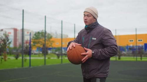 Young Man Practicing Basketball Skills on Outdoor Court