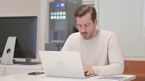 Coughing Young Man Using Laptop in Office