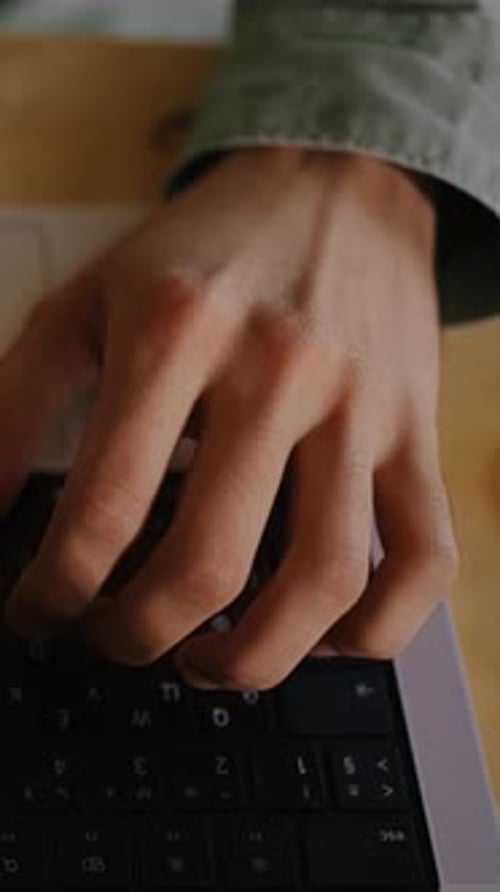 Man with Curly Hair Types on Laptop Keyboard