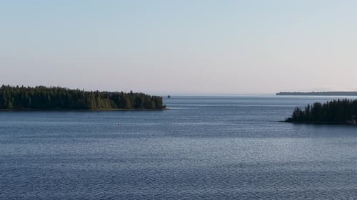 Aerial drone footage of a calm lake with tree-lined islands and distant horizon in Michigan’s Upper