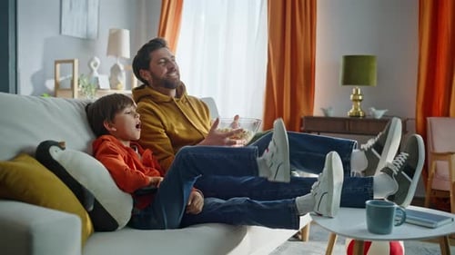 Father and Son Relaxing on Couch Watching TV